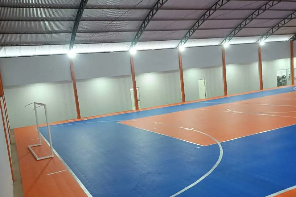 Depois: Quadra em piso modular azul e laranja, com travamento de perímetro e folga de dilatação executados conforme o 